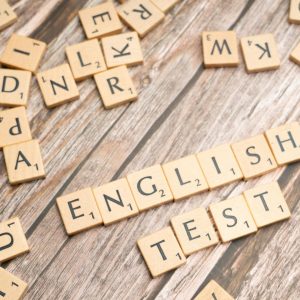 Wooden Scrabble tiles spelling out 'English Test' on a wooden background, ideal for language exam themes.