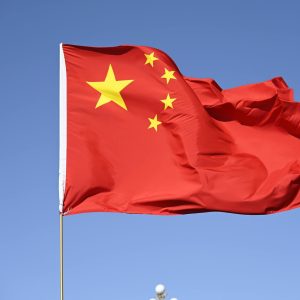 Chinese national flag flying high against a clear blue sky, symbolizing unity and pride.